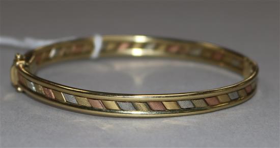 A 9ct three-colour gold hollow hinged bangle, 9.9gr